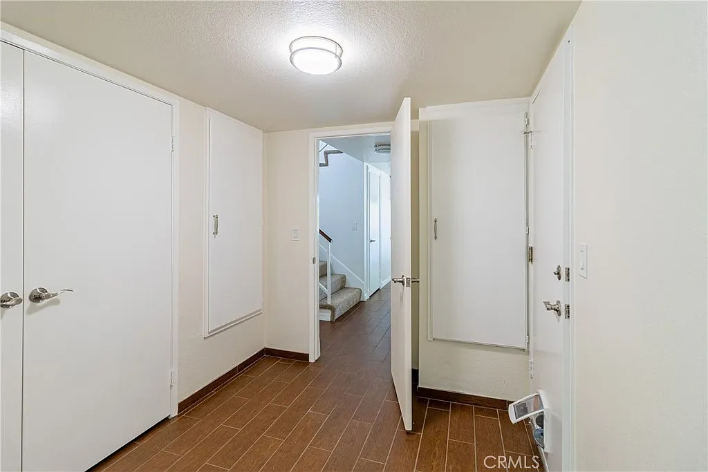 Hallway with two closed doors on left, staircase in background, and light-colored walls and floor.