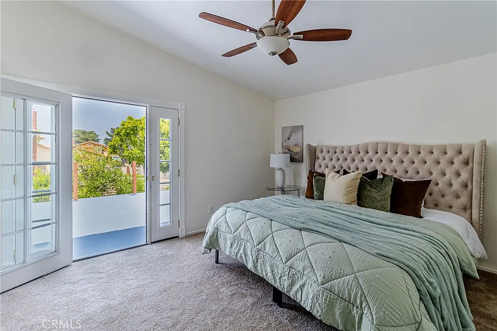 Bedroom with tufted headboard, white bedside lamps, green throw blanket, light-colored walls, and two framed artworks above bed.