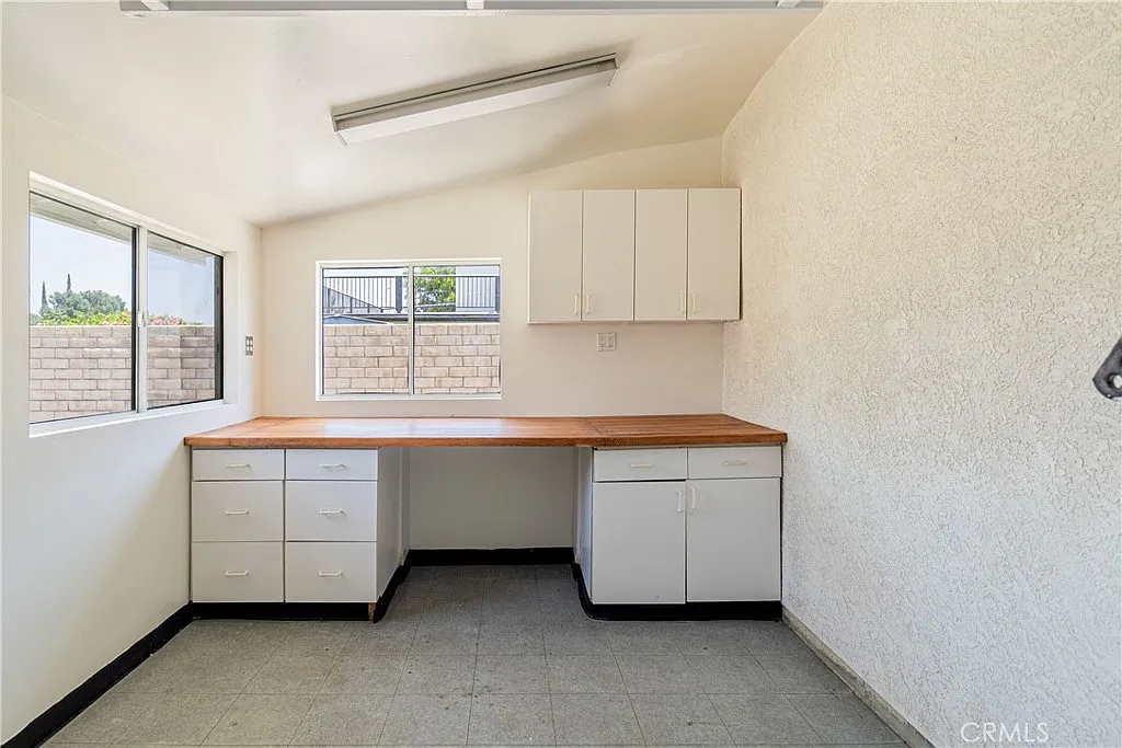 Spacious empty room with countertop, cabinets along walls, and windows with natural light.