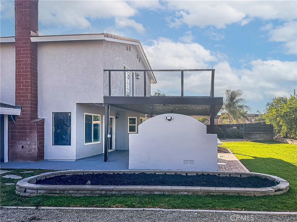 Two-story house with patio cover, grassy yard, and landscaped area, real estate.