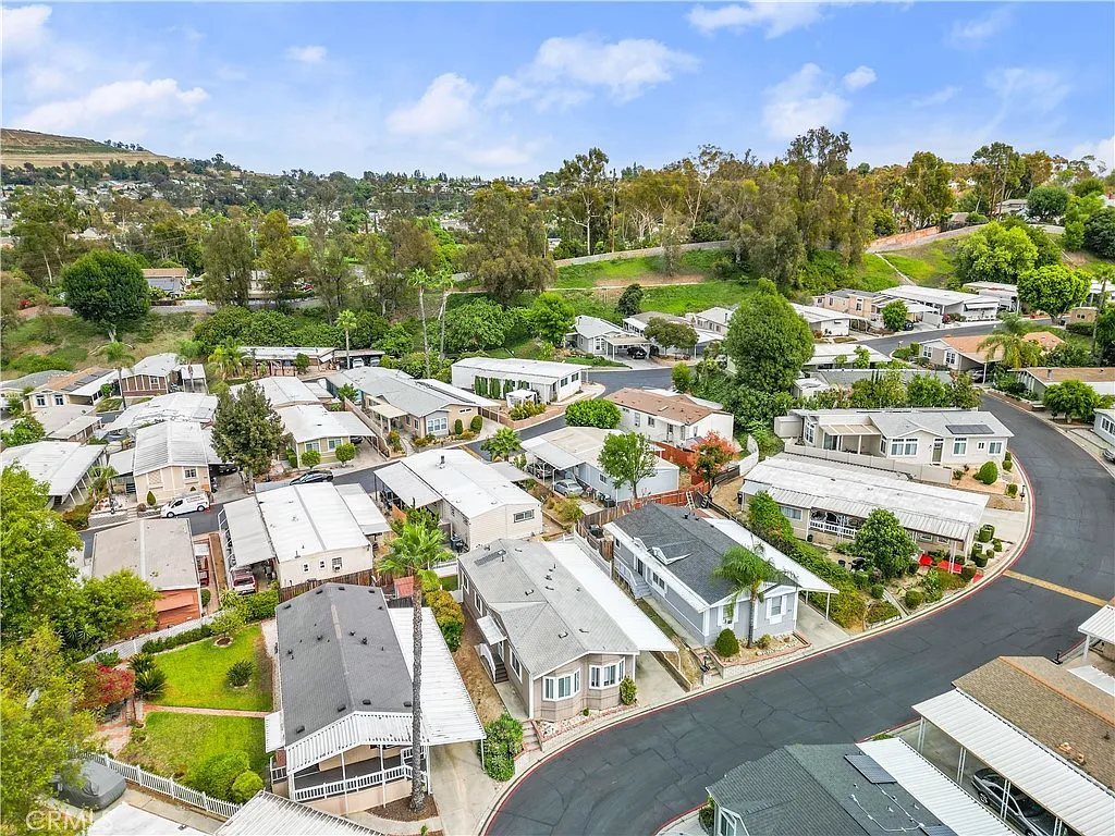 Aerial view of neighborhood with mobile homes, greenery, and hills, California real estate.