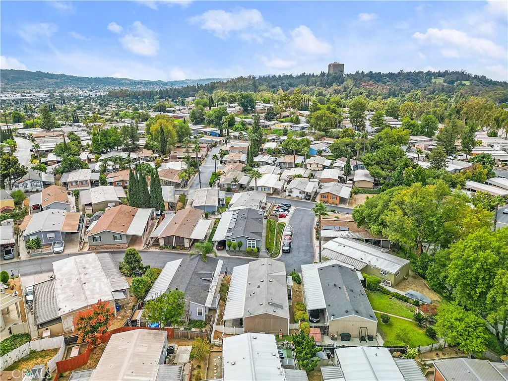 Aerial view of suburban neighborhood with houses, trees, winding roads, and greenery, California real estate.