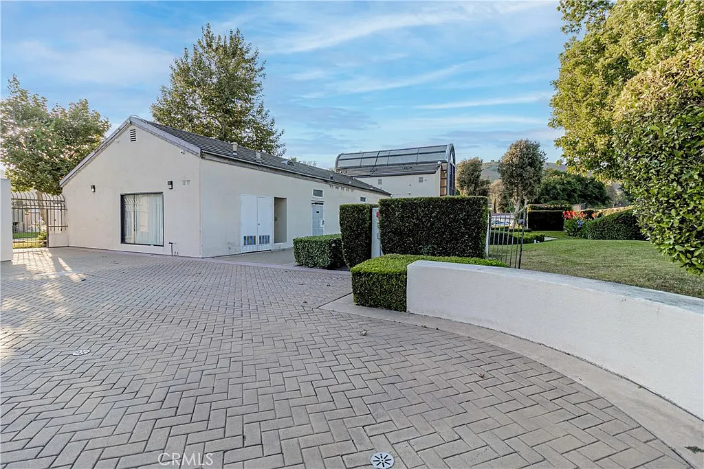 Modern house with paved driveway, landscaped greenery, white exterior, and large windows, real estate.