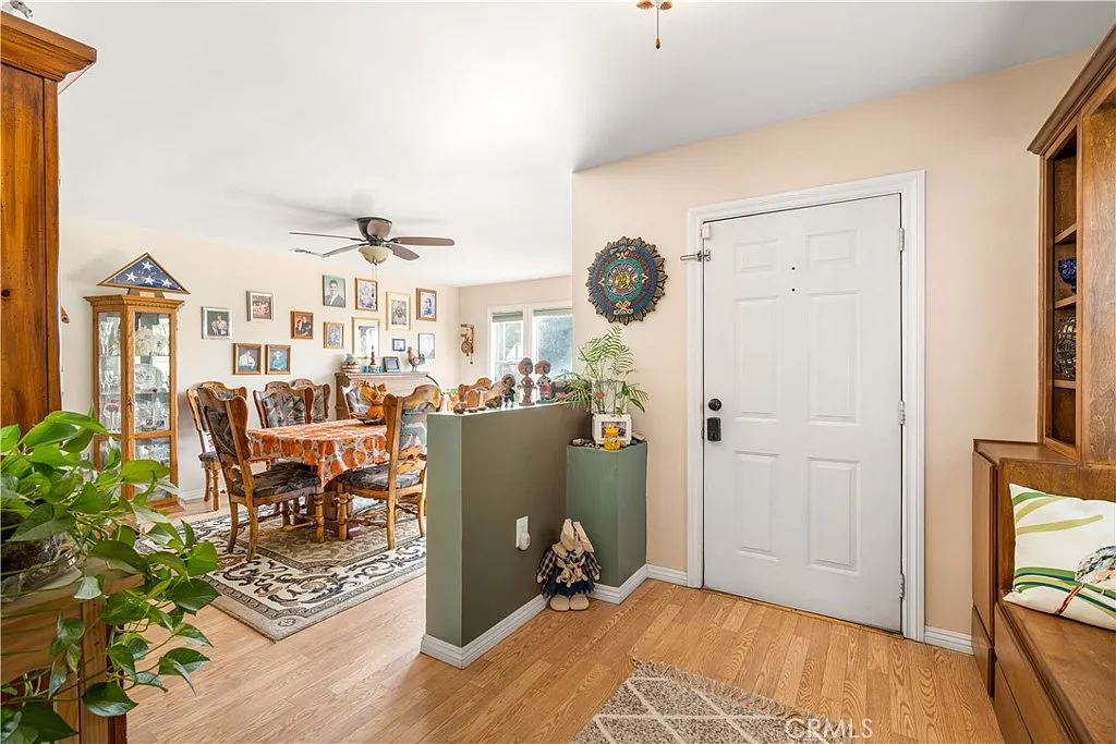 Entrance area with a front door, decorative plants, and a dining area with framed pictures visible in the background.