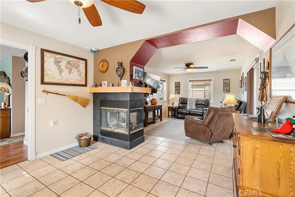 Living room with tile floor, fireplace, big windows, wall map, and chairs.