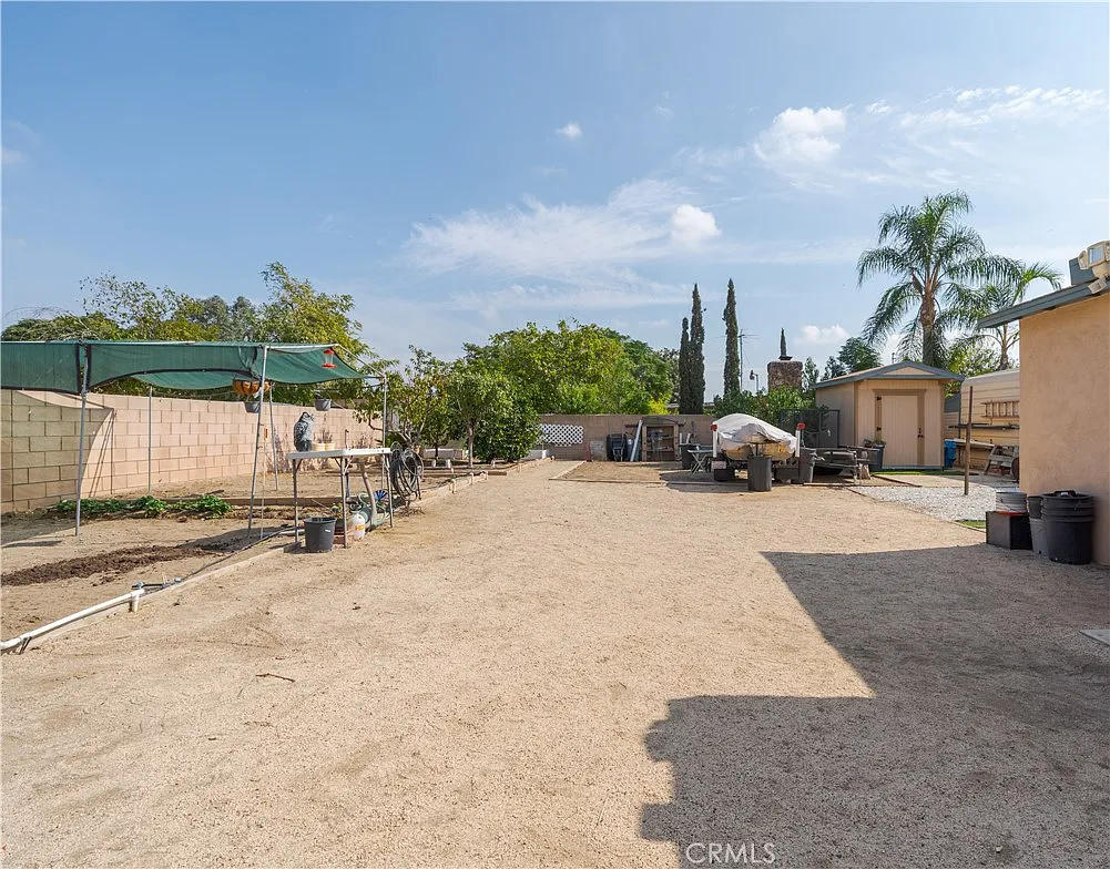 Outdoor area with dirt ground, scattered structures, trees, and equipment