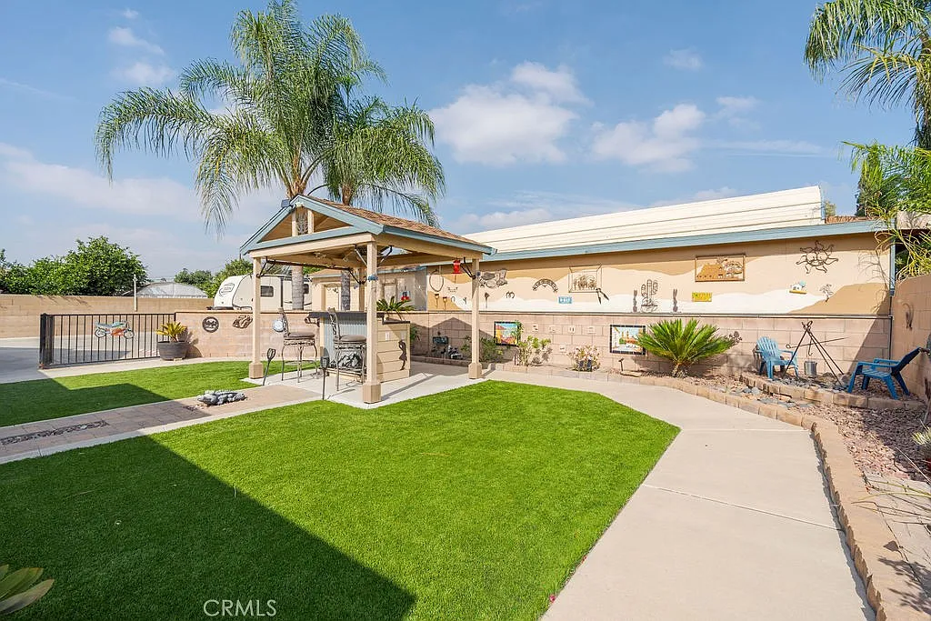 Backyard with covered gazebo, green grass, and decorative wall elements