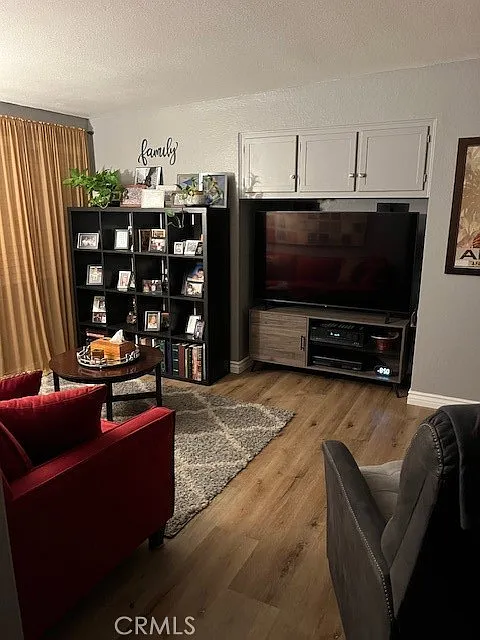 Living room with a red chair, gray couch, TV unit, bookshelf with pictures, and curtains.