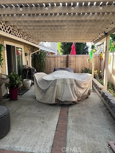 Covered outdoor hot tub in a patio with a pergola and surrounding plants.