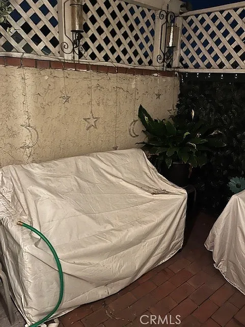 Covered sofa in a patio with a green garden hose, star-themed wall decorations, and plants.