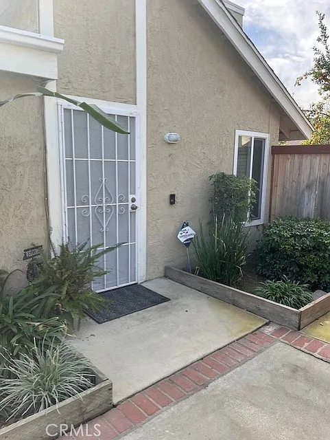 Front entrance of a house with a screened door, welcome mat, and planters on both sides.