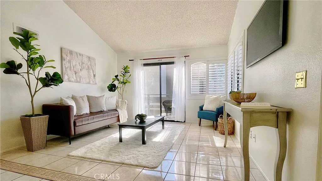 Living room with couch, coffee table, decorative plants, and sliding doors to balcony.