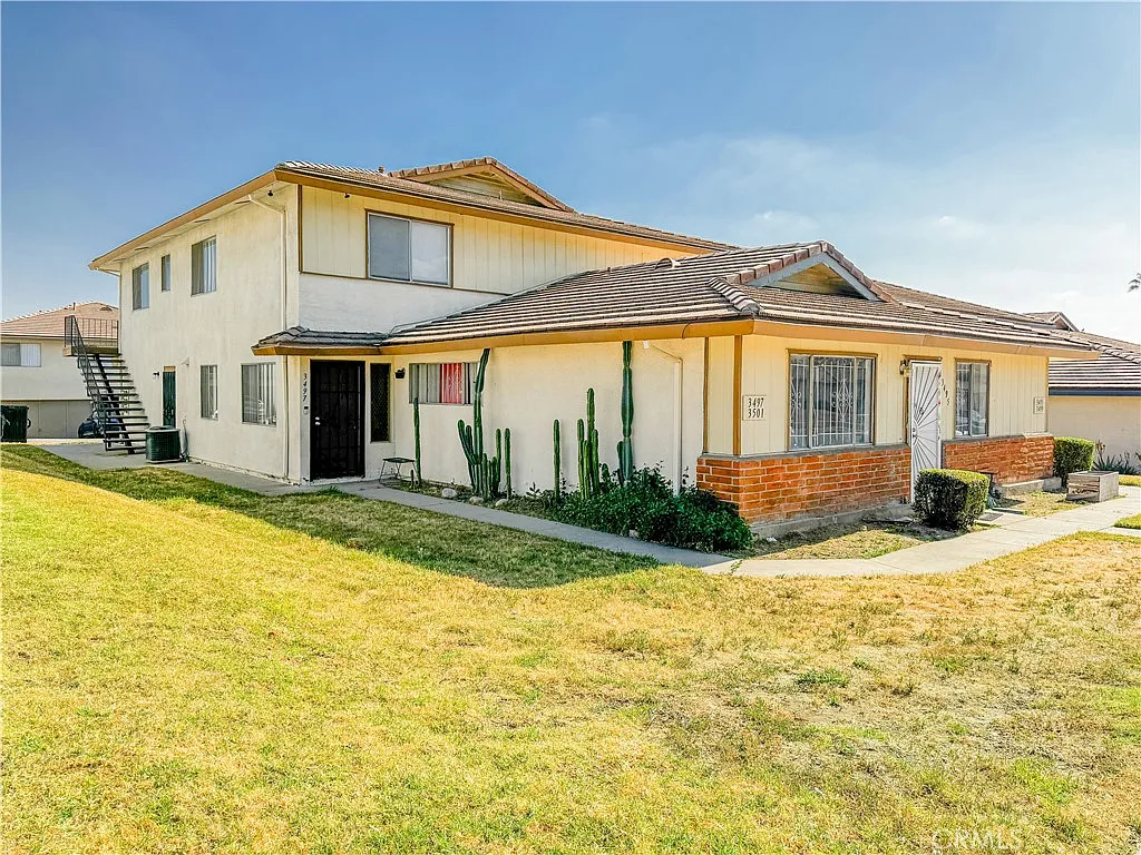 Two-story house with landscaped front yard, cactus plants, and walkway to entrance, real estate.