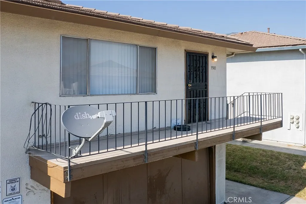 Balcony with railing and satellite dish attached to a building.