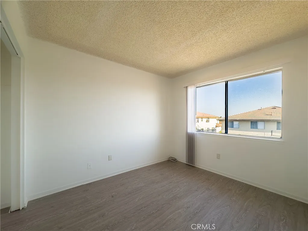 Vacant room with white walls, large window, natural light, and light-colored floor
