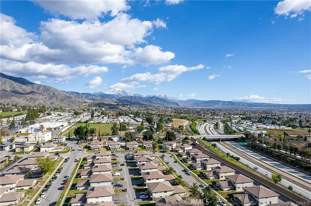 Aerial view of suburban area with houses, roads, and mountains in the background.