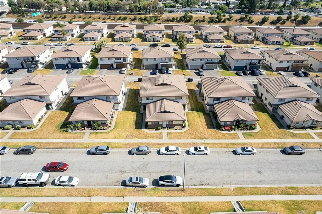 Aerial view of neighborhood with similar houses and parked cars along the street.