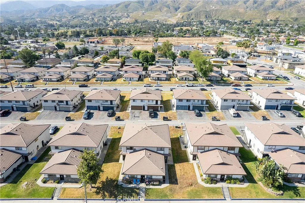 Aerial view of neighborhood with rows of houses and mountains in the distance.