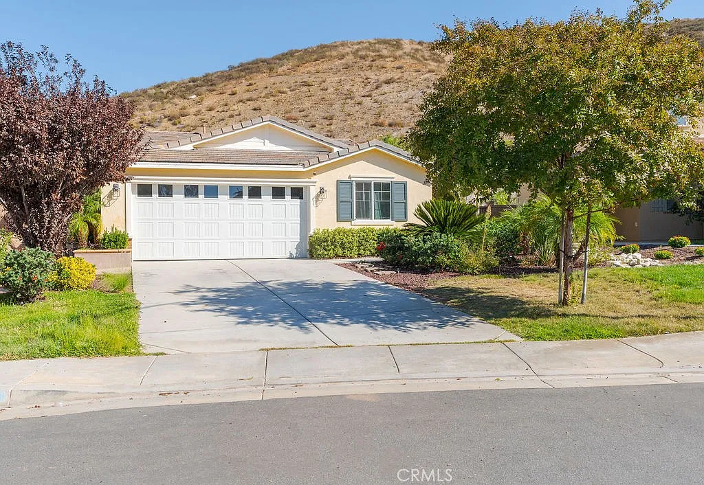 Single-story house real estate with front yard, driveway, and nearby hillside.