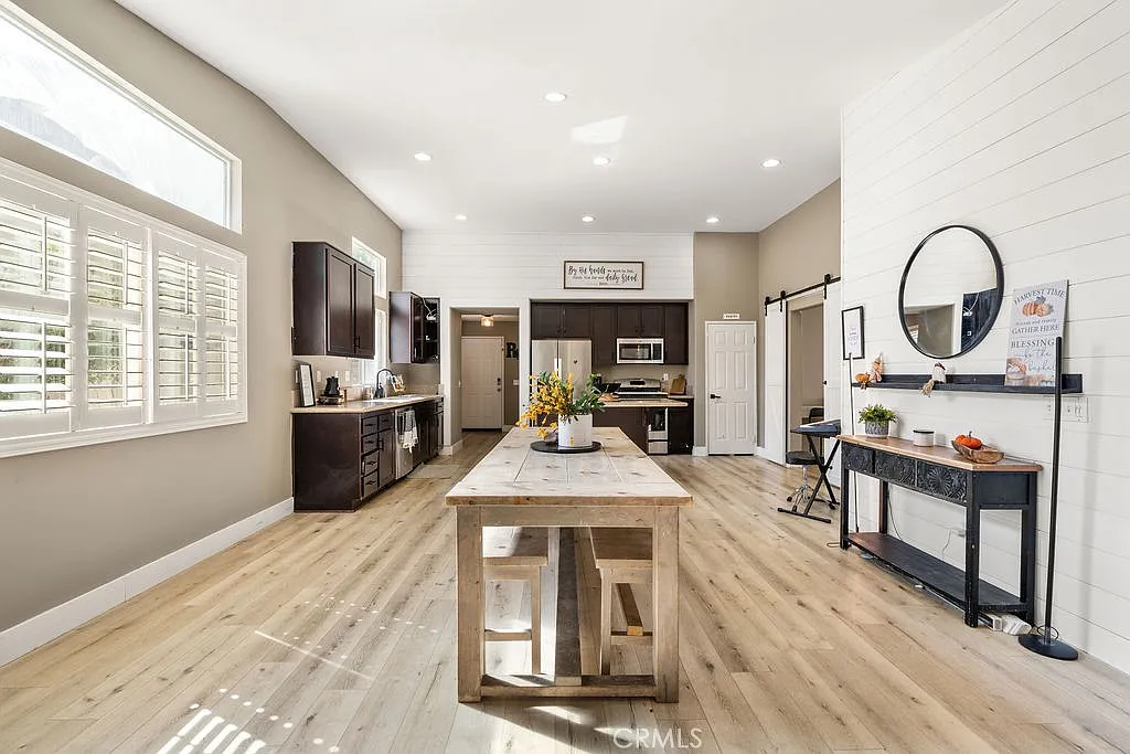 Kitchen with wooden floors, large central dining table, modern appliances, and light and dark cabinets.