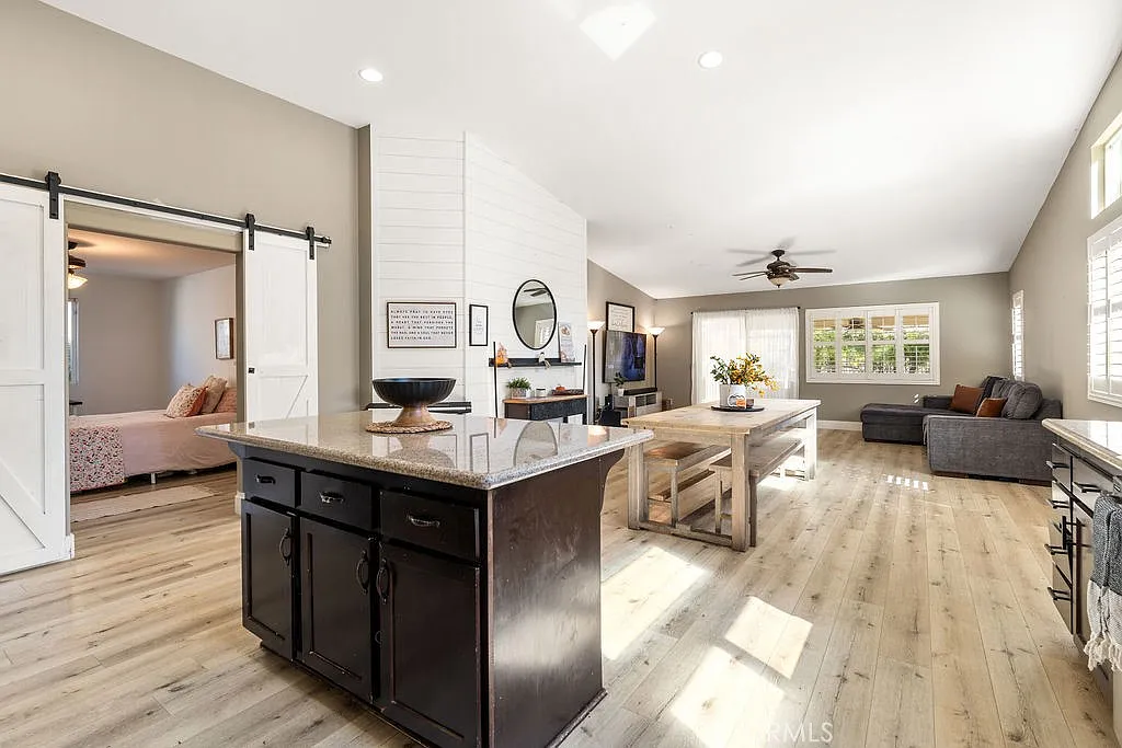 Kitchen with dark wood cabinets, stainless steel appliances, large central island, natural light from windows, and decorative wall signage.