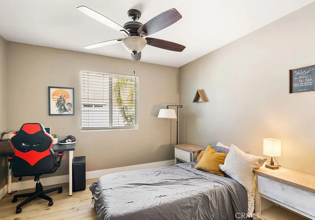 Bedroom with bed with gray bedding, desk and chair, ceiling fan