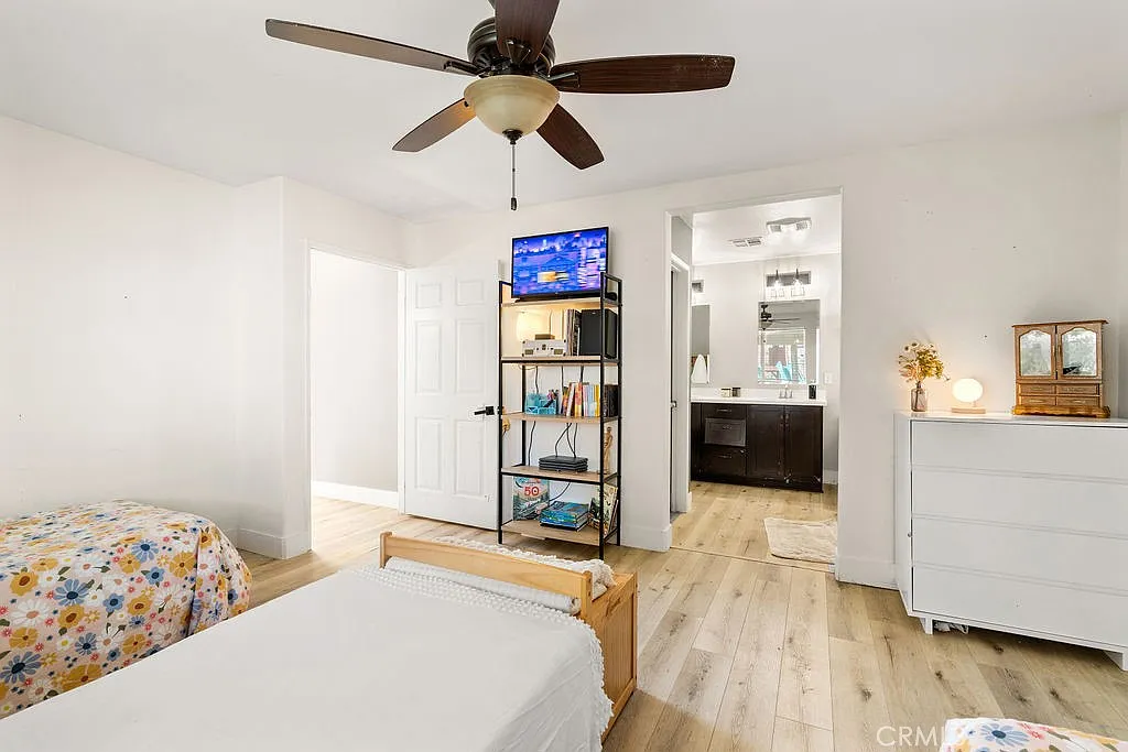 Bedroom with wood bed, white bedding, ceiling fan, large window, and mirror.