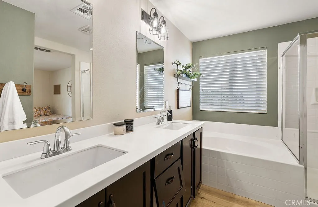 Bathroom with double sink vanity, mirrors, shower, window blinds, and green accents.