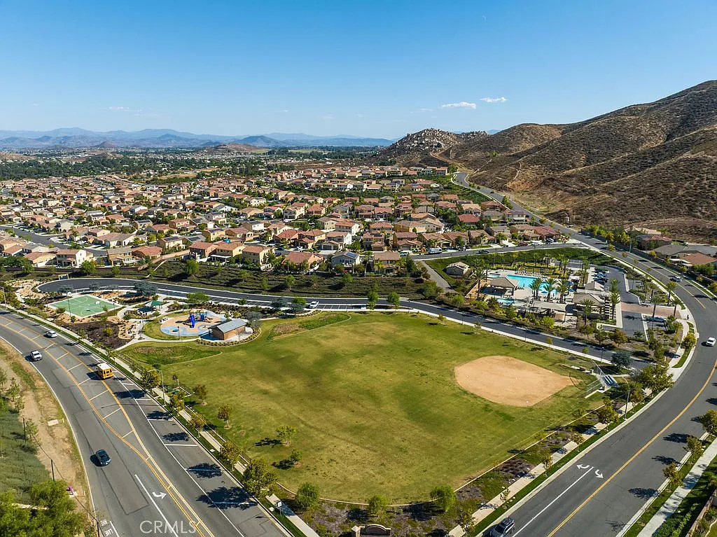 Aerial view of a residential area with houses, a park, nearby mountains
