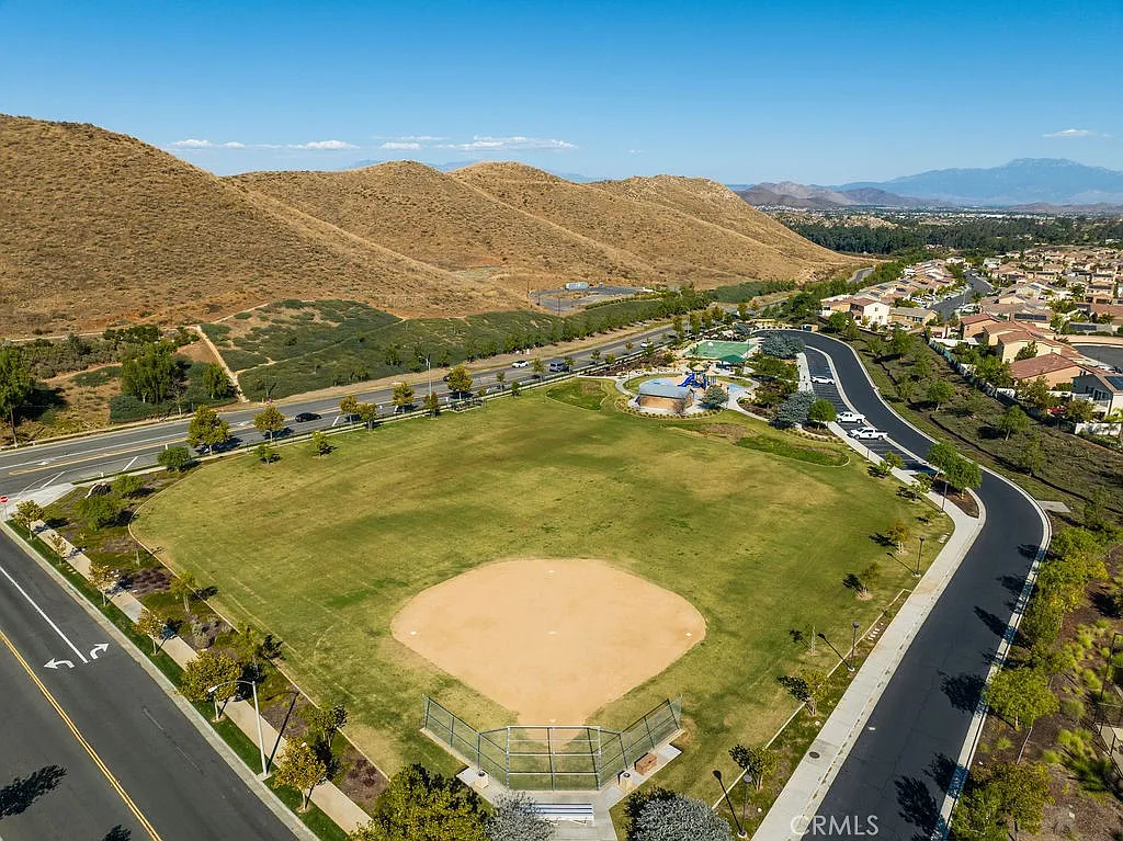 Aerial view of a park with a baseball diamond, hills, and nearby residential areas.