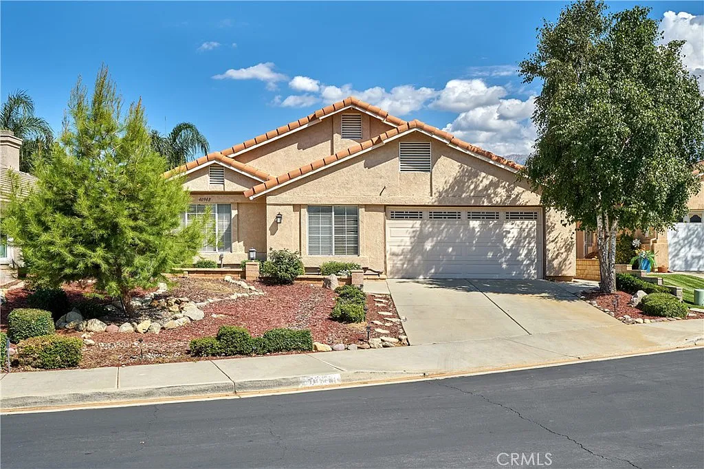 Single-story house California real estate with tan walls, tile roof, garage, and front yard.