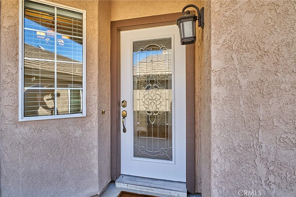 Front door with decorative glass, window with blinds, beige textured walls