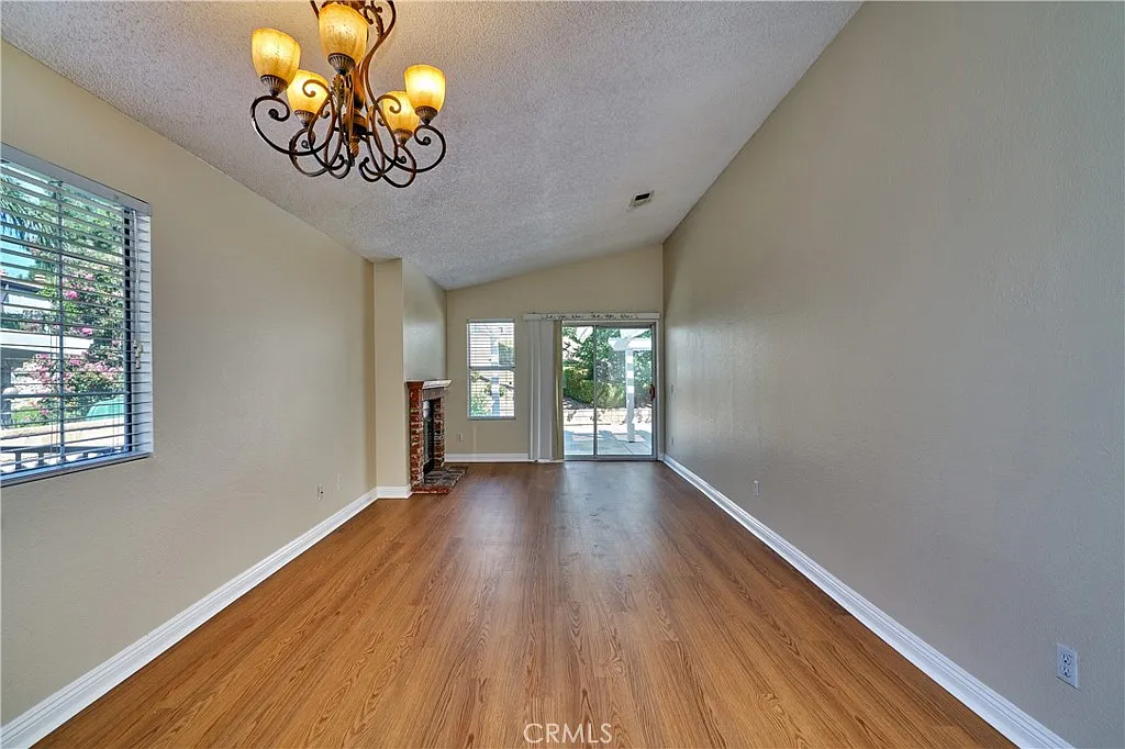 living room with high ceilings, chandelier, fireplace, large windows, sliding glass doors, and hardwood floor.