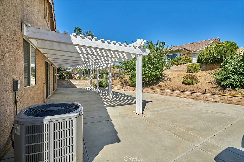 Patio with concrete floor, air conditioning unit, and landscaped hills and shrubs, California real estate.