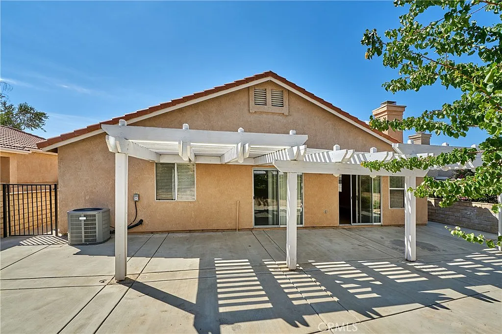 Single-story house with patio, white pergola, trees, California real estate.