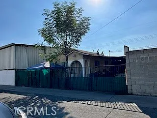 House with green awning, trees in front, and fenced yard.