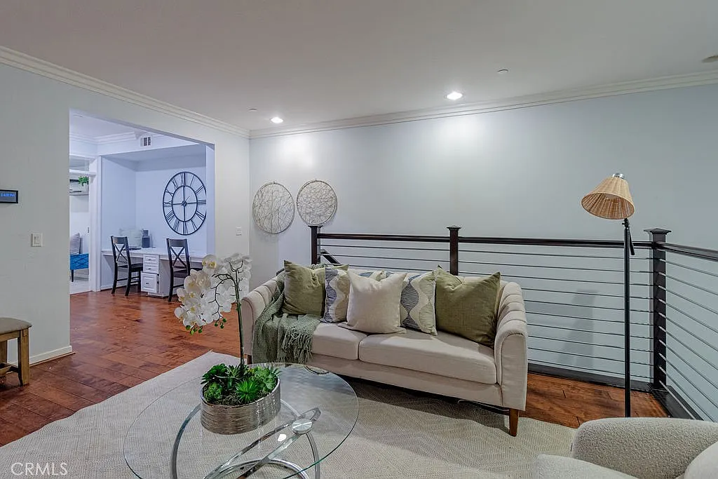 Living room with light-colored couch, decorative pillows, glass coffee table with plant, and modern decor.