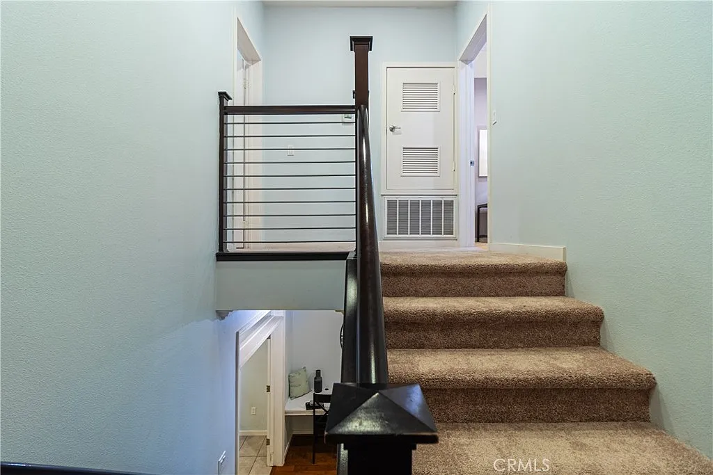 Staircase with railing, light blue walls, leading to hallway on upper level.