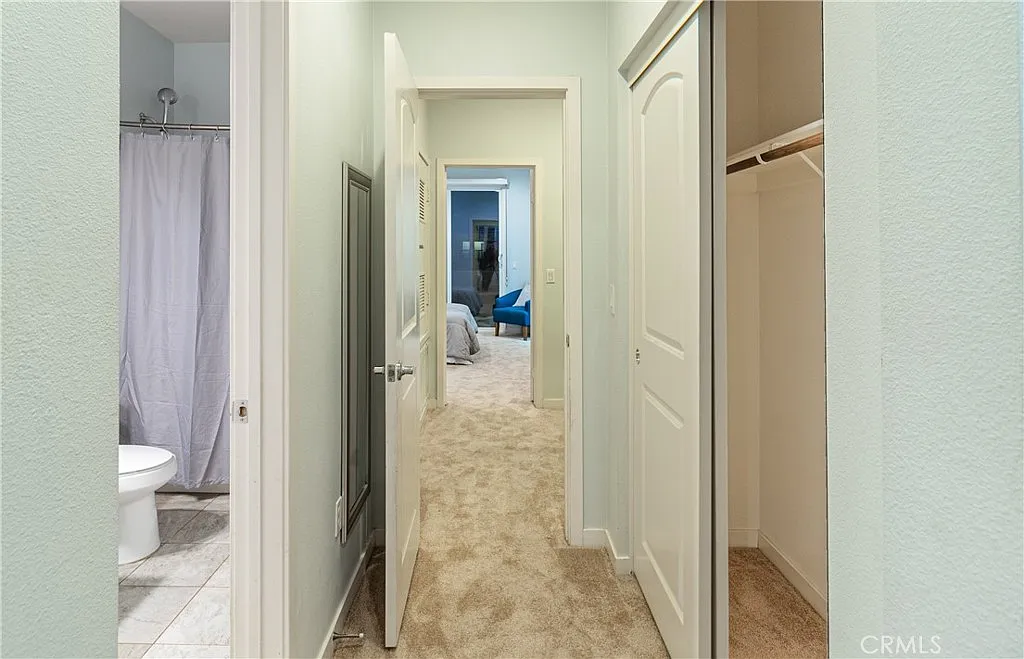 Hallway with closet on right, leading to bathroom and room at the end.