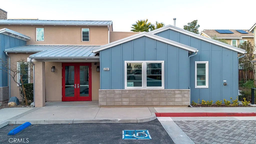 Blue and gray house real estate with red door, porch, and front plants.