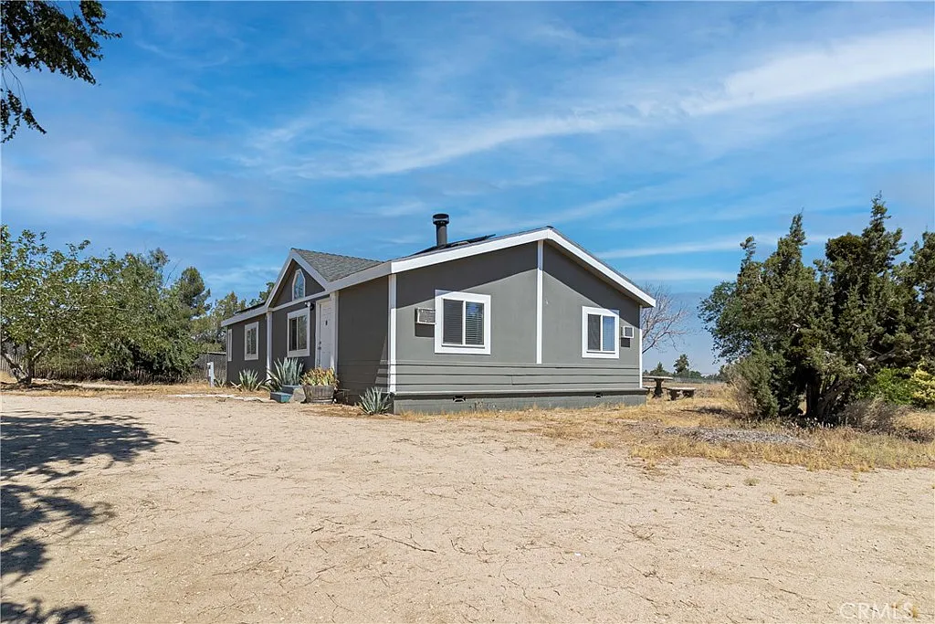 Gray house real estate with white trim, open land and few trees