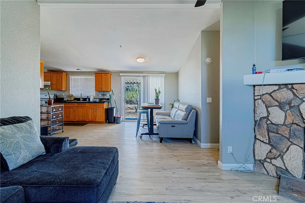 Living room with dark sofa, light walls, open kitchen with wooden cabinets, and dining table.