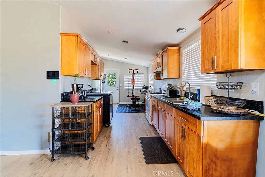 Kitchen with wooden cabinets, black countertop, open layout, and visible workout area.