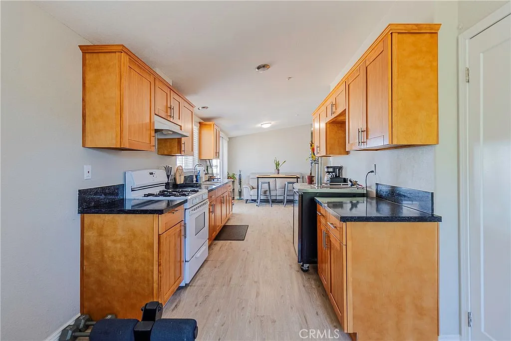 Kitchen with wooden cabinets, dark countertops, stainless steel appliances, and window light.
