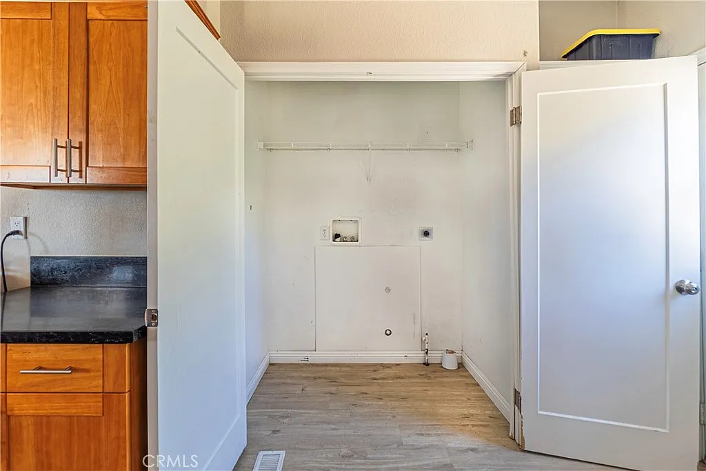 Vacant laundry room with wooden cabinets, countertop, and open door to empty space
