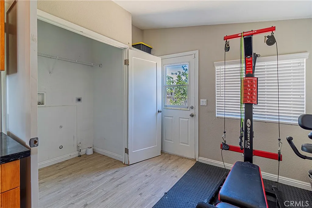 Small home gym with exercise equipment, doorway, closet, light walls, and window with blinds.