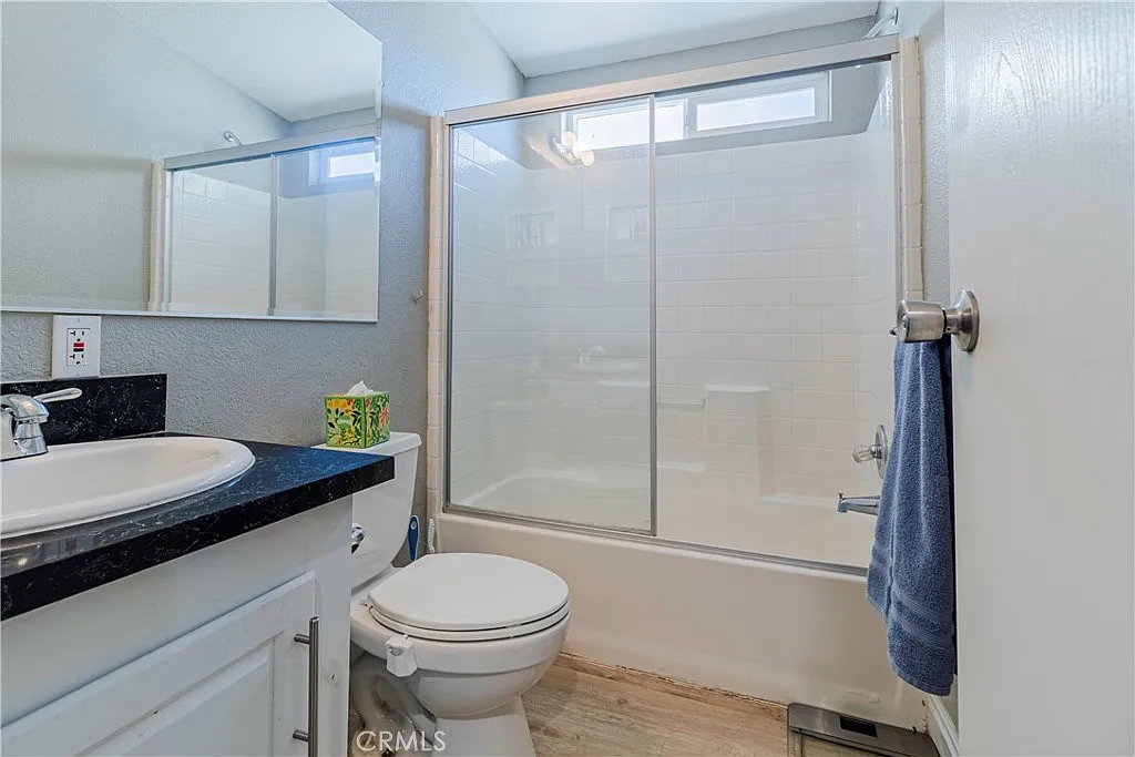 Bathroom with glass shower, toilet, sink, and countertop space.