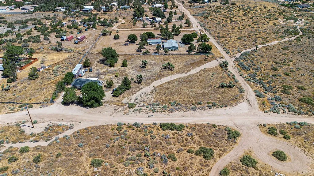 Aerial view of rural area with dirt roads, sparse vegetation, and scattered houses.