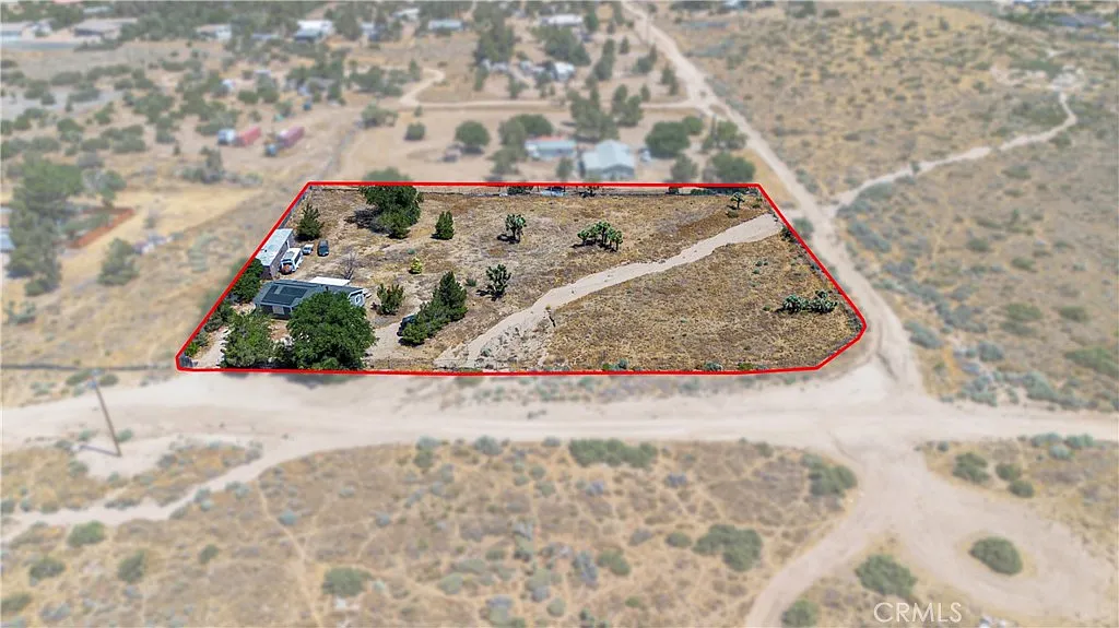 Aerial view of rectangular plot of land with vegetation, road, and nearby properties in rural area.