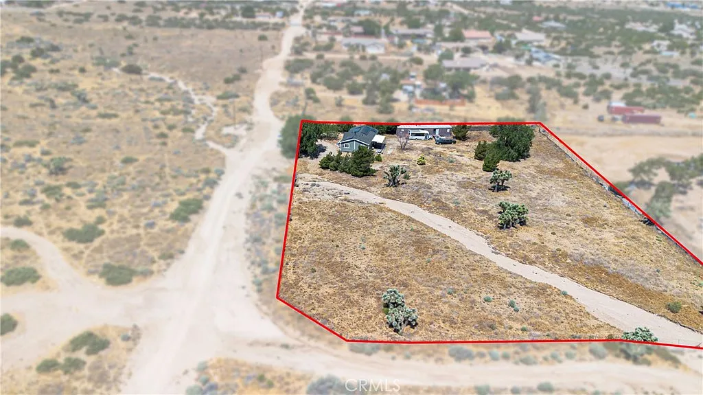 Aerial view of property outlined in red with dry land, sparse vegetation, and dirt road.
